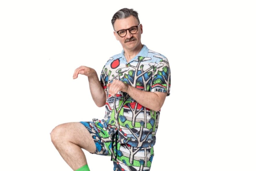 A performer wearing bright shorts and a matching shirt, holding a silly pose, as part of the NGV Kids Summer Festival.