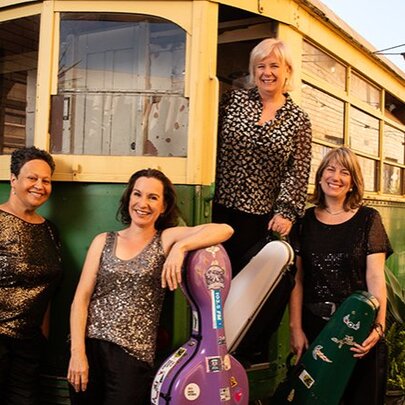 The four female members of the Flinders String Quartet posing in front of a vintage yellow and green Melbourne tram.