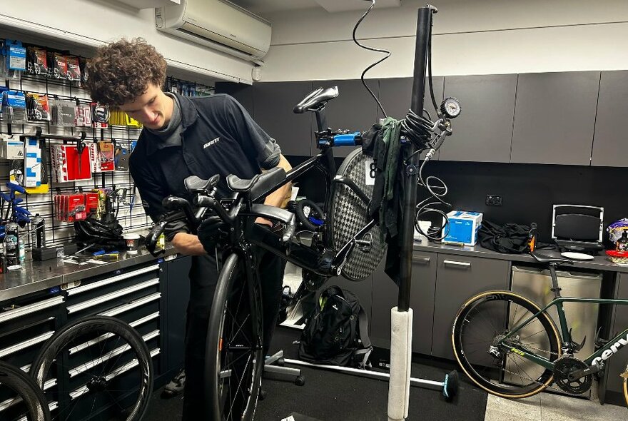 A technician works on a bicycles inside a shop.