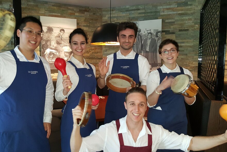 The smiling waiters at La Camera, posed and holding small musical instruments.