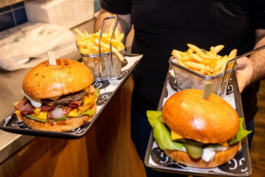 Person carrying two burgers and chips.