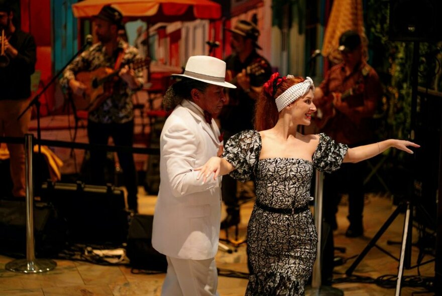 A couple Latin dancing in front of a live band playing music.