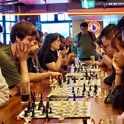People playing social chess at a table in a pub.