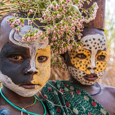 Children from a tribe in the Omo Valley of Ethiopia with traditional face painting standing outside.