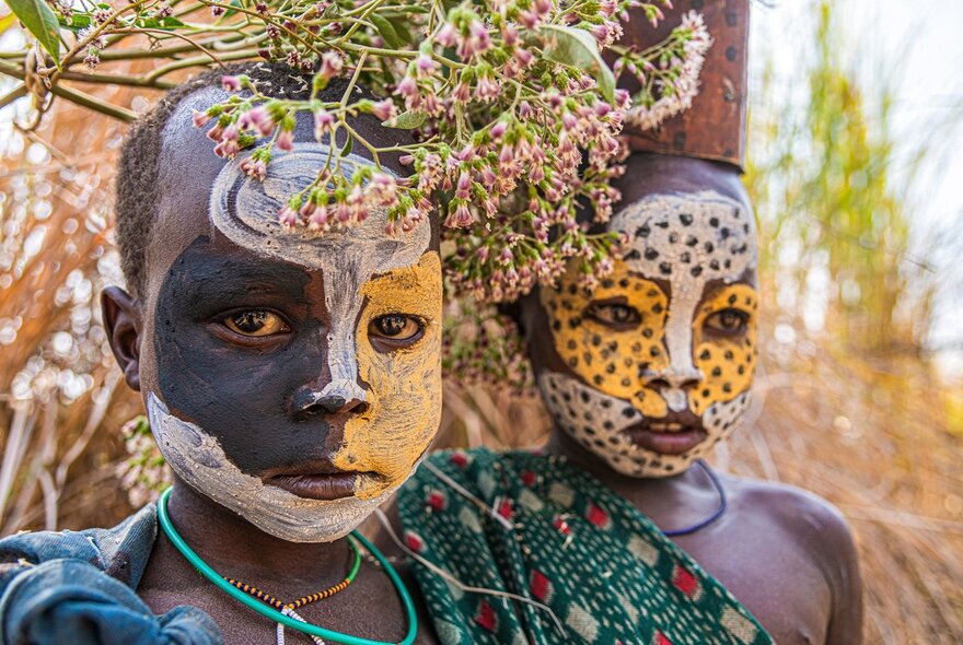 Children from a tribe in the Omo Valley of Ethiopia with traditional face painting standing outside.