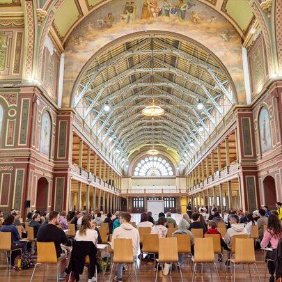 People seated in chairs in the great exhibition space in the Royal Exhibition Building, Melbourne.