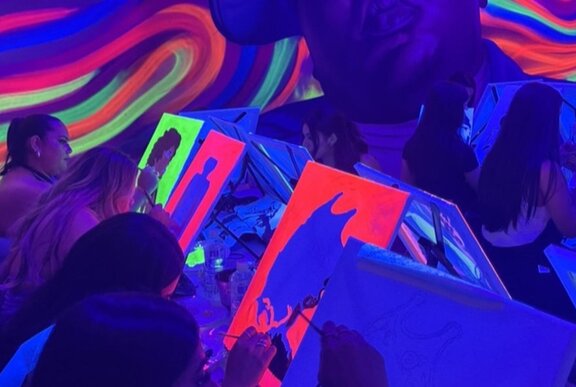 People painting in a glow in the dark room with swirling colours.