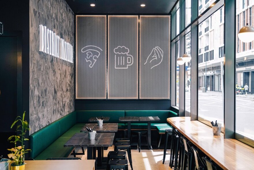 The interior of a small restaurant with several tables and window seating. 