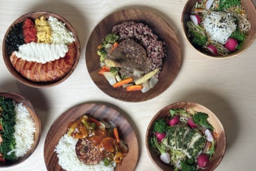 Overhead view of several dishes of healthy Asian food on wooden plates.