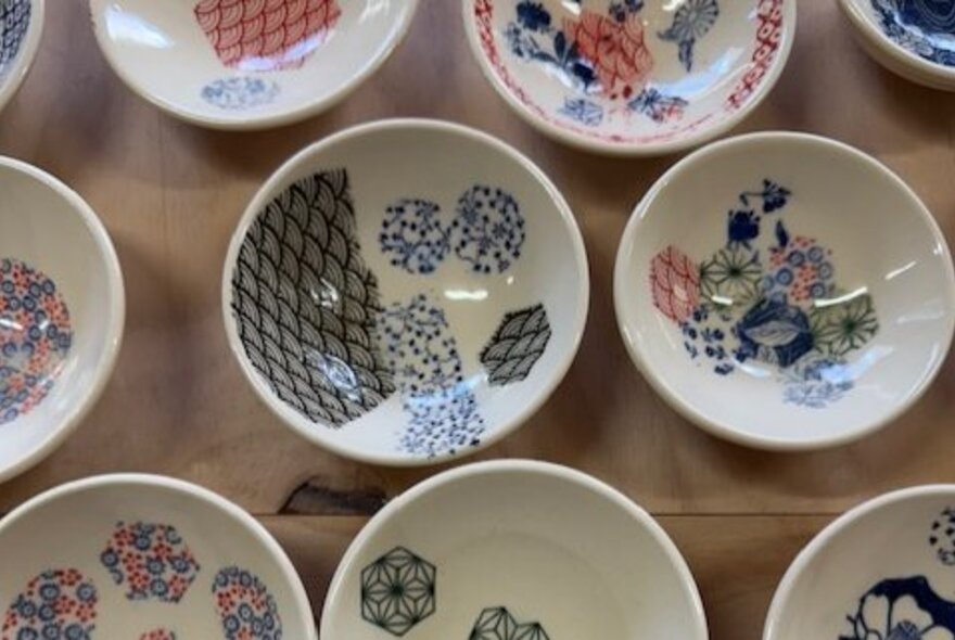 A collection of small white ceramic bowls with handpainted Japanese-style artwork.