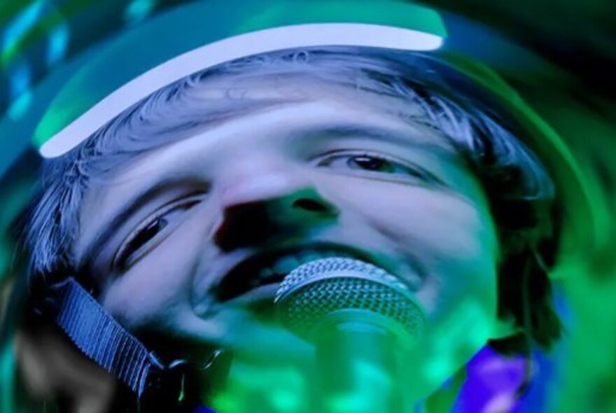 Warped image of a person singing into a microphone in psychedlic blues and greens.