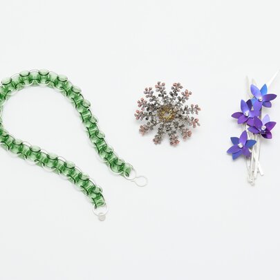 Three contemporary art jewellery pieces arranged horizontally against a plain white background.