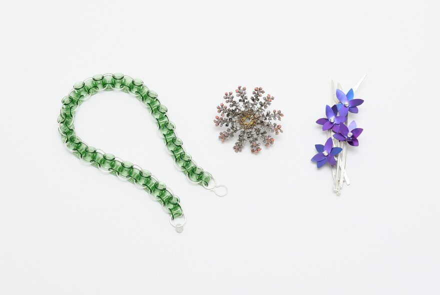 Three contemporary art jewellery pieces arranged horizontally against a plain white background.