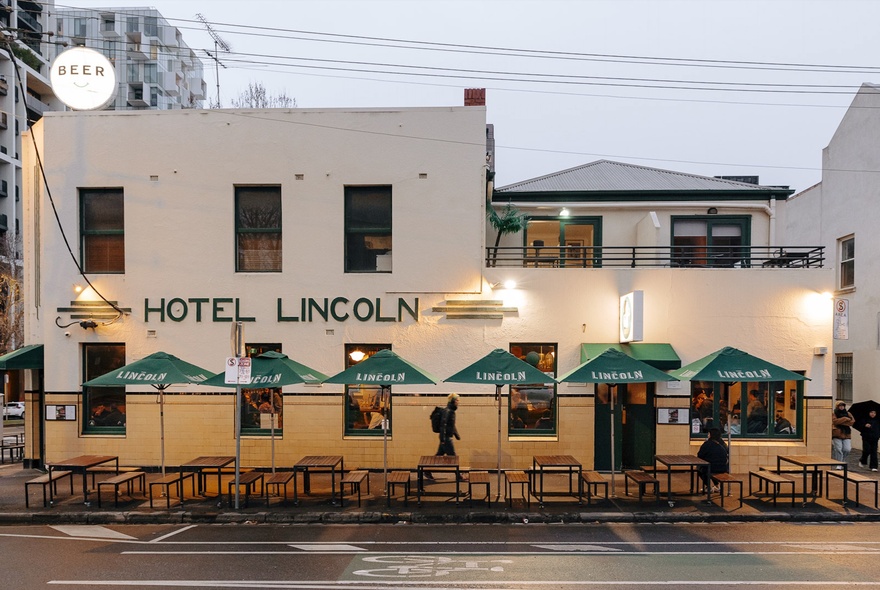 Hotel Lincoln exterior with signage and outdoor tables with umbrellas.