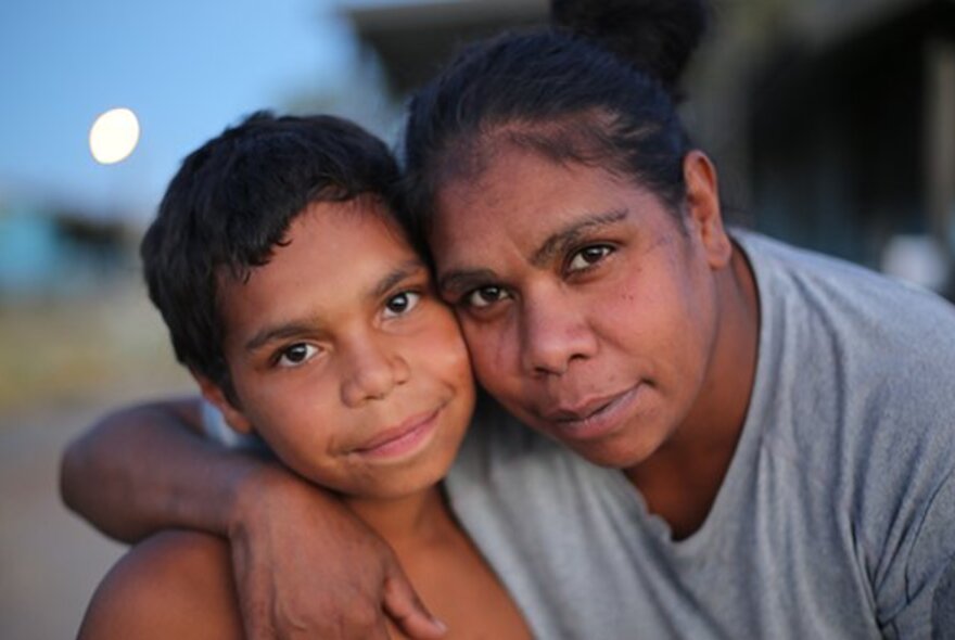 Still from the film 'In My Blood it Runs' with a smiling boy smiling and his mother with her arm around his shoulder drawing him close to her face.