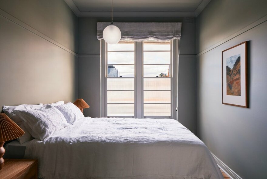 Hotel suite at The Courthouse Hotel, with a queen size bed in the bedroom, a glass door against the rear wall. 