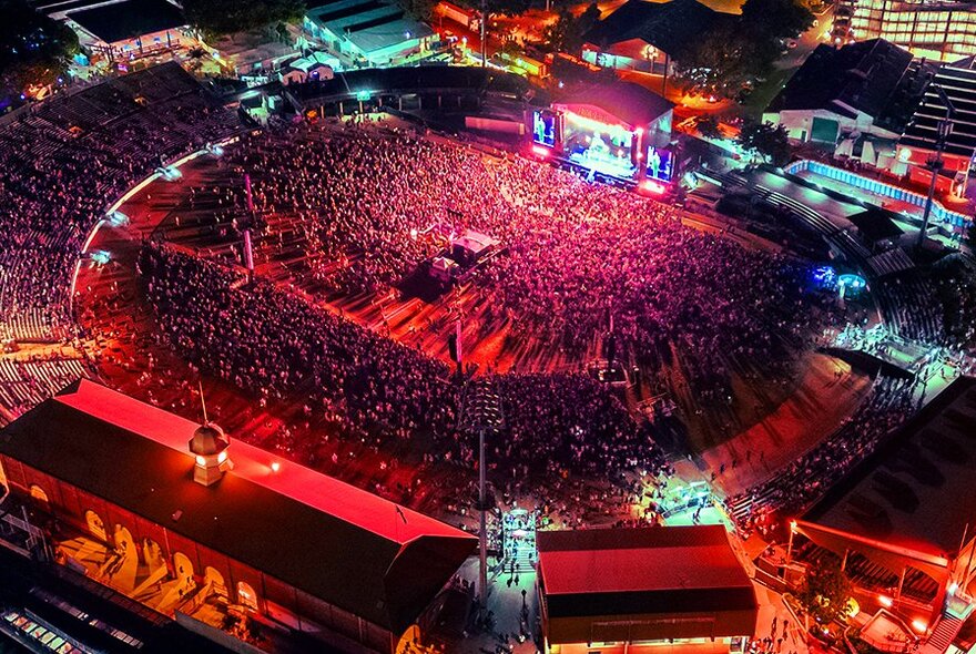Huge crowded stadium bathed in red light, viewed from above.