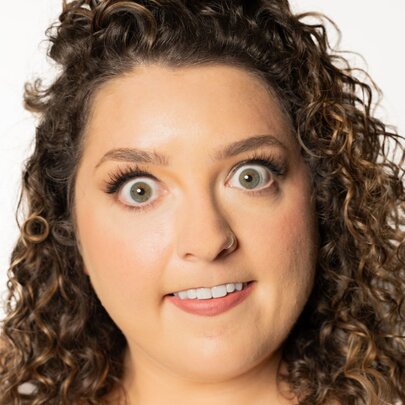 A close up of a woman's face showing her wide-eyed, biting her bottom lip.