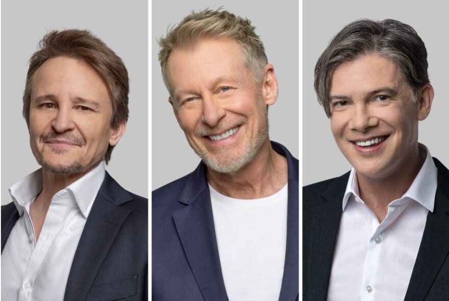 The actors Richard Roxburgh, Damon Herriman, and Toby Schmitz - three middle aged men smiling at the camera all wearing dark suit jackets and white shirts.