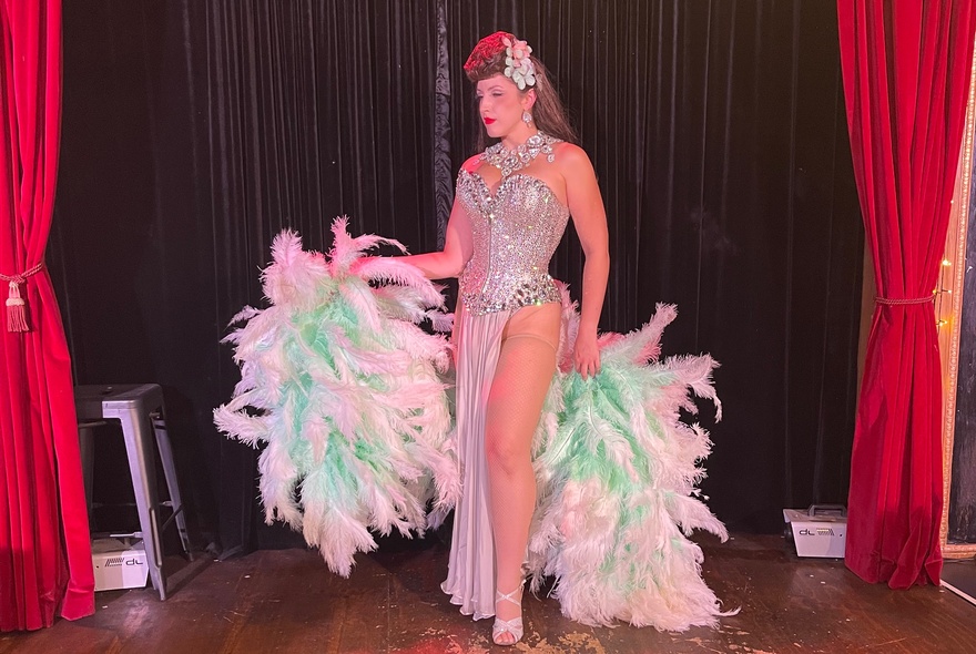 A burlesque performer with feathered fans. 