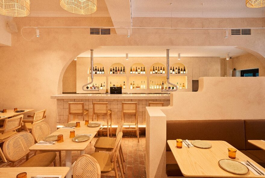 Restaurant interior in palest pink decor, with cafe tables and seating and backlit bar.