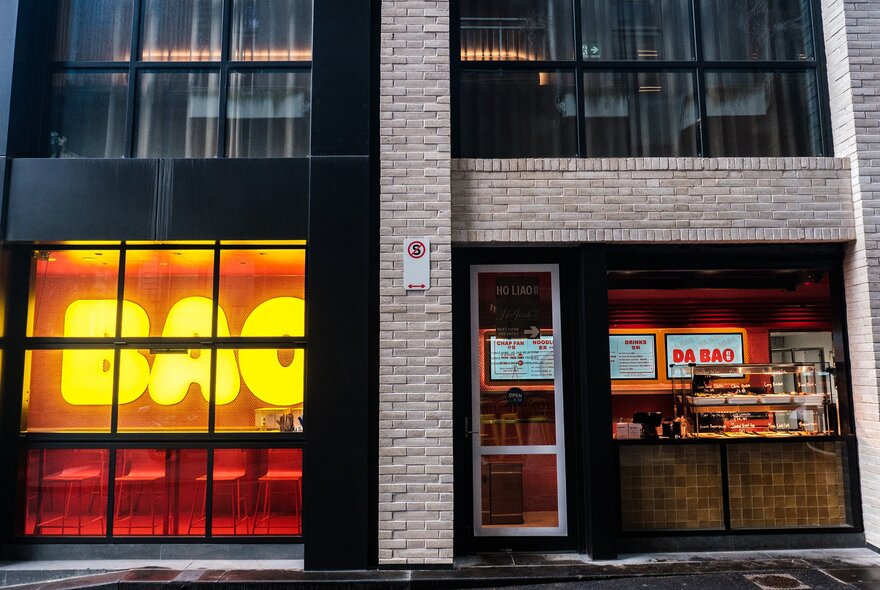 The exterior of a hole-in-the-wall Malaysian restaurant. There is a big neon sign saying Bao.