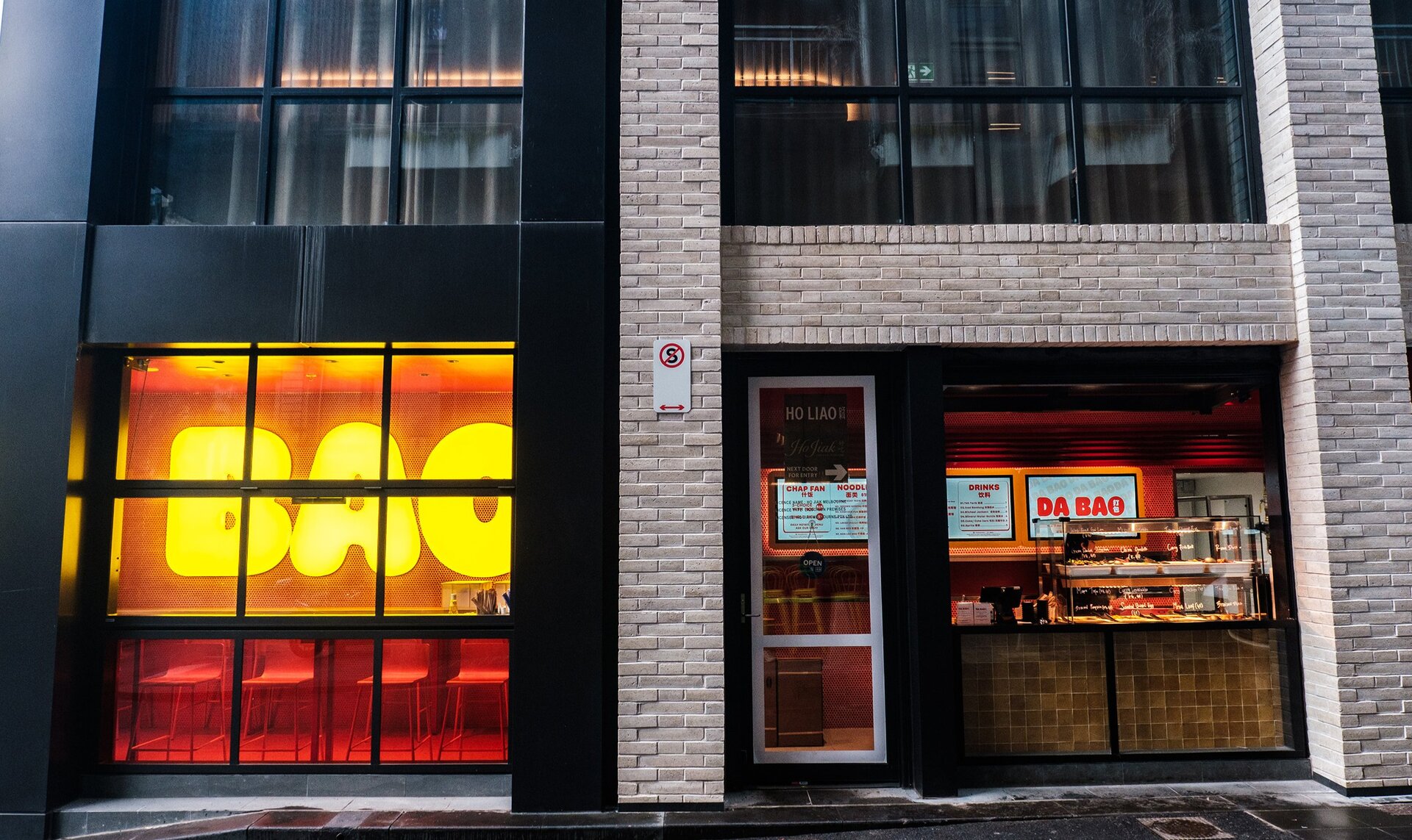 The exterior of a hole-in-the-wall Malaysian restaurant. There is a big neon sign saying Bao.