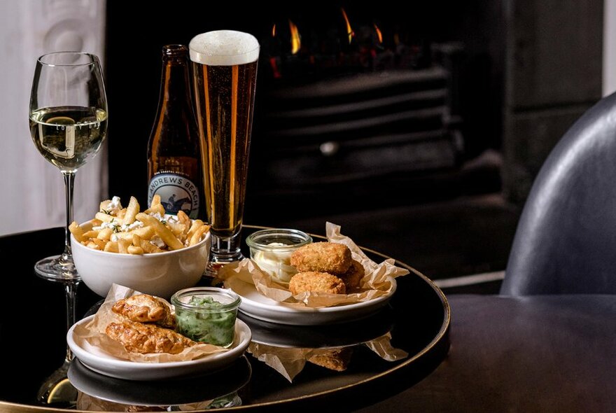 Glass of wine, beer and snacks on a small table.