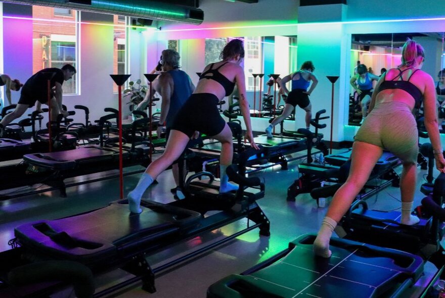 People exercising on a Megaformer machine in a studio space.