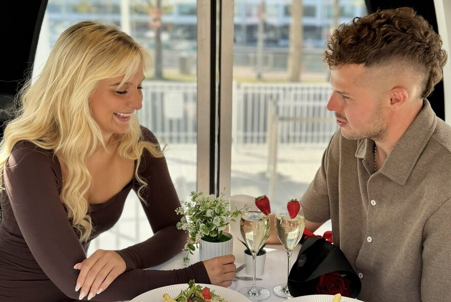 A couple having a meal together inside a gondola on the Skyline Melbourne Ferris Wheel.