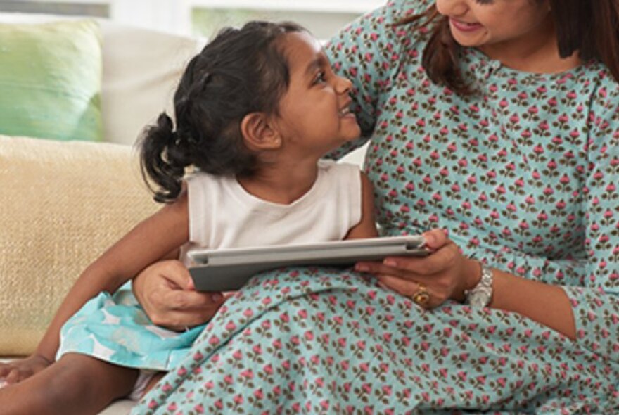 Mother and child seated on a couch with a book.