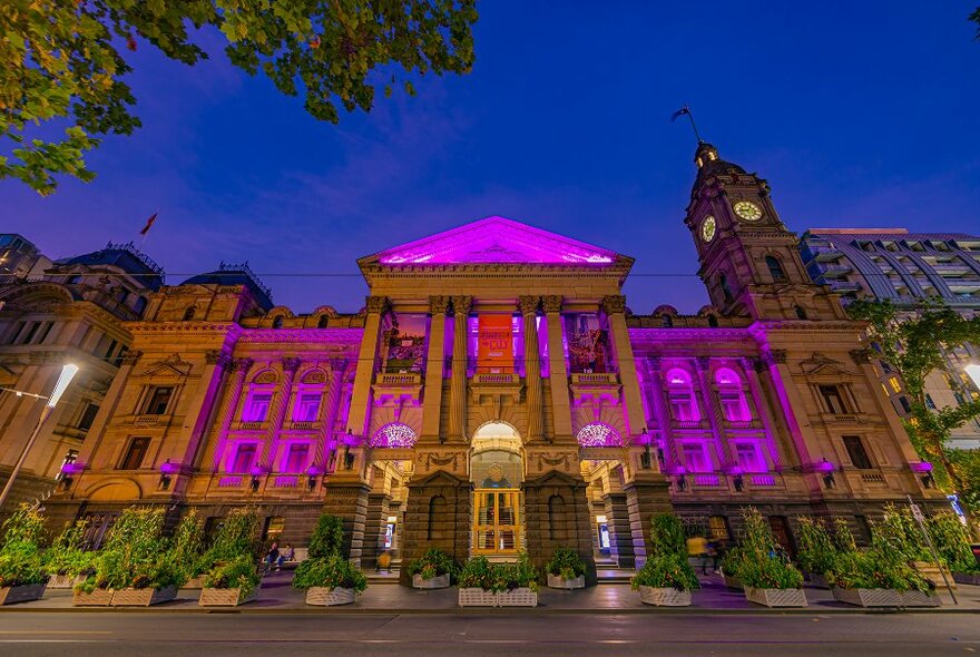 Melbourne town hall illuminated purple at night.