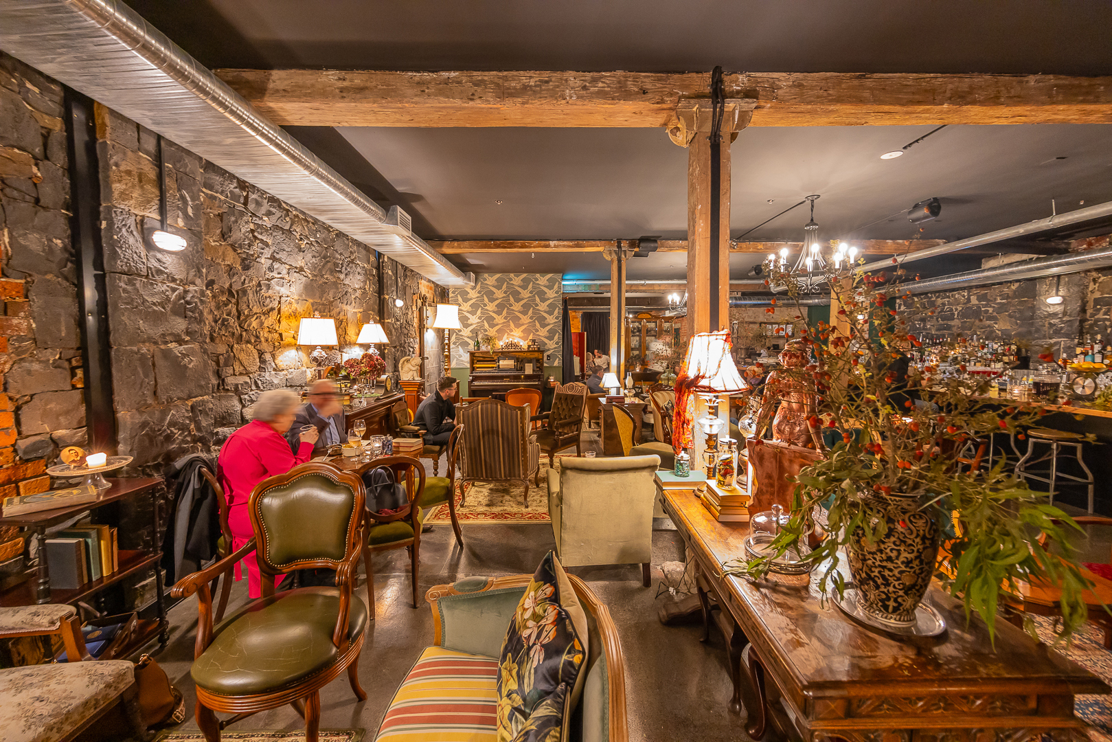 A warmly lit bar with people sitting in antique furniture.