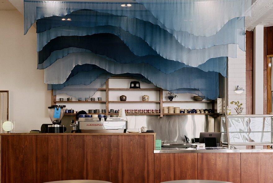 The interior of Vietnamese cafe and restaurant, Cham, with blue hanging curtains looking like waves hanging above the wood-lined counter.