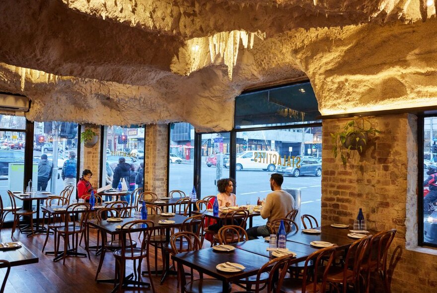 The dining room of a restaurant with an interesting cave-like roof.