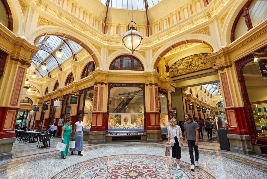 Four people with shopping bags walking inside a heritage shopping arcade.