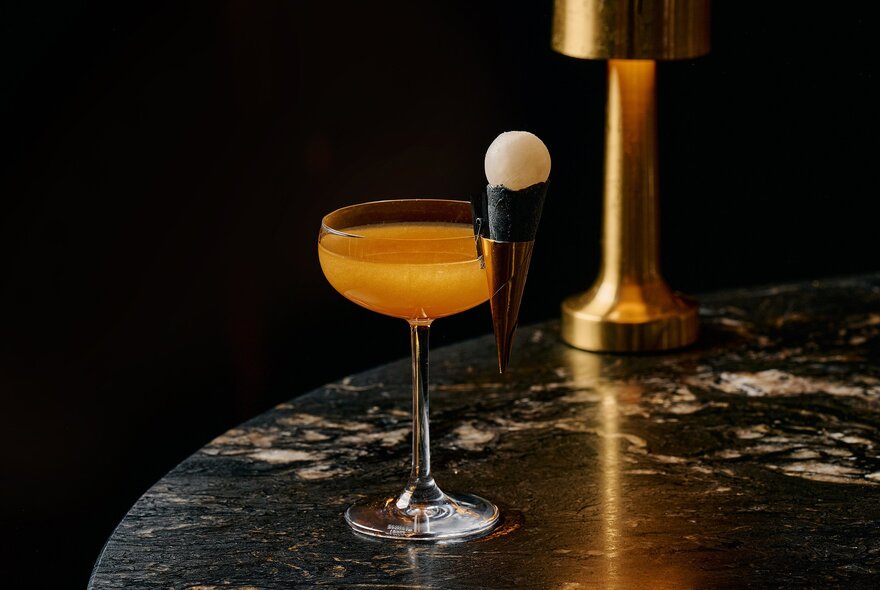 Cognac-hued cocktail on a round marble table.