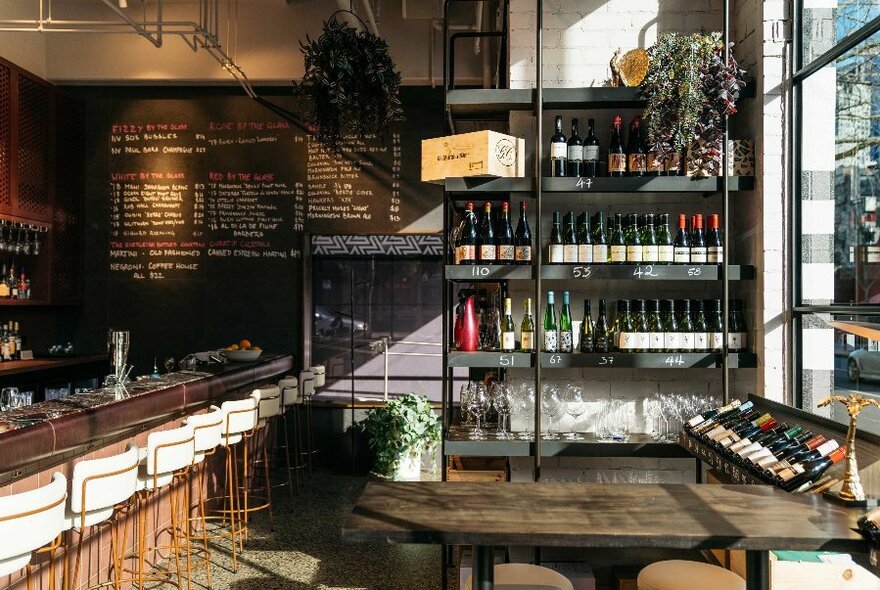 Cocktail and wine bar interior with bottles, blackboard sign and long bar.