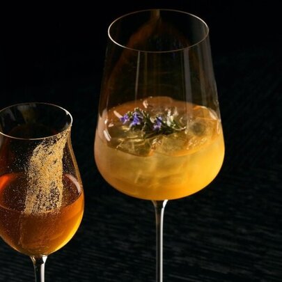 Two cocktails in different shaped glass, against a black background.