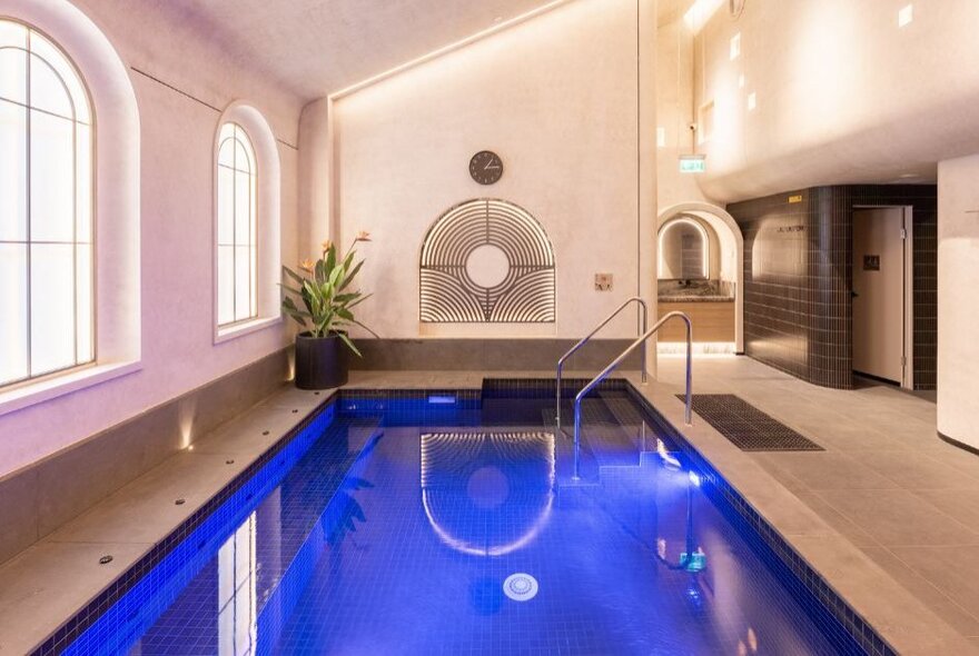 An indoor mineral bathing pool at the Arima Spa, featuring soft lighting, arched windows, and a minimalist Japanese design. 