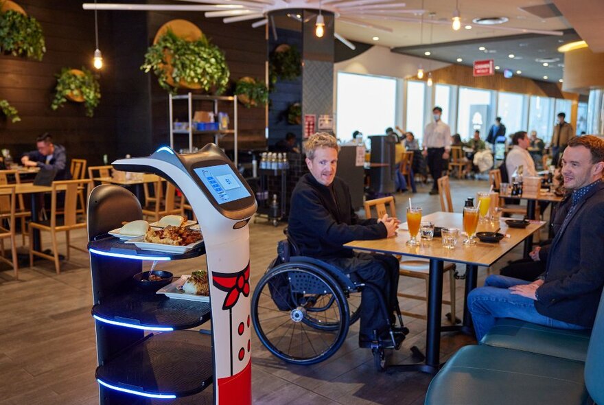 A group of friends are in a Chinese restaurant they are being served by a robot waiter