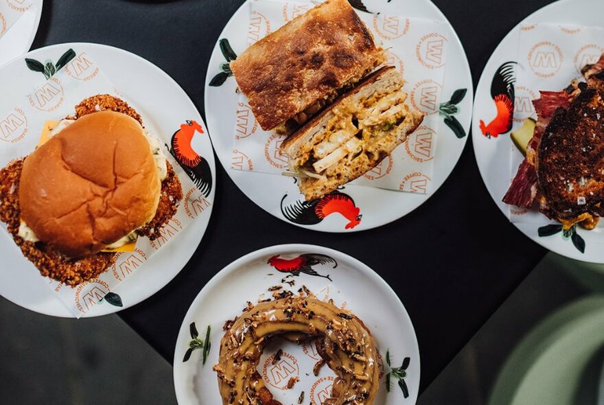 Looking down on an assortment of plates containing sandwiches and pastries.