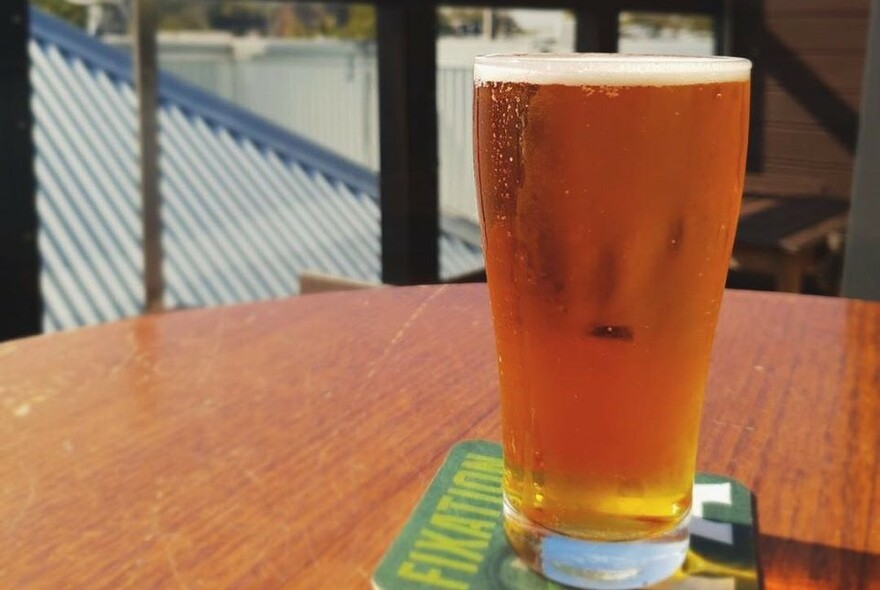 Bar table with a glass of beer on a beermat.