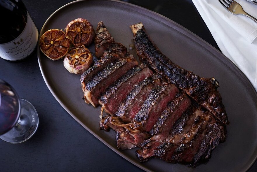 Looking down on a dark plate filled with charred, sliced meat.