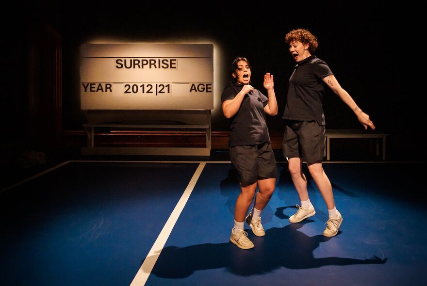 A theatre set with two children playing on a tennis court, court signage in the background.
