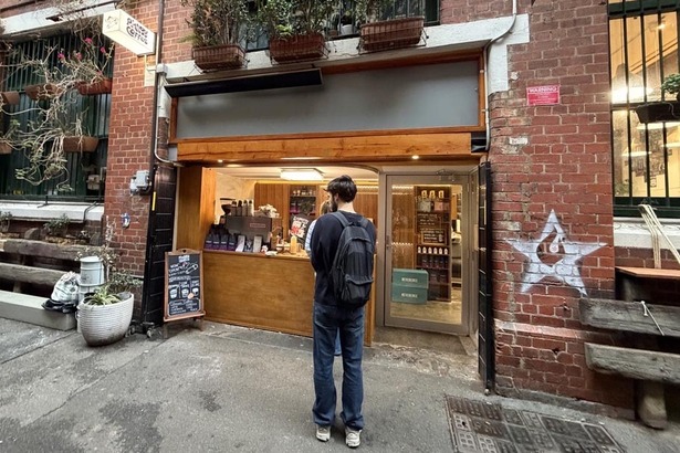 A man ordering from a  laneway coffee window. 