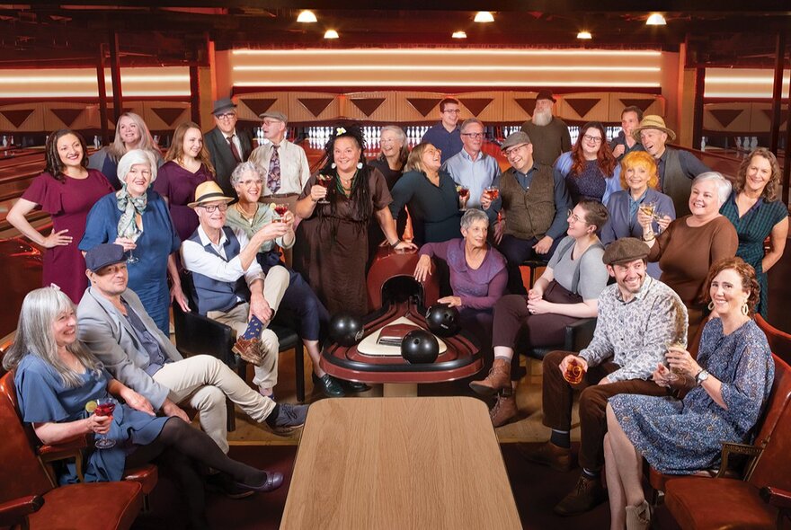 The members of Sweet Monas Choir, some seated and some standing inside the lanes at a bowling alley.