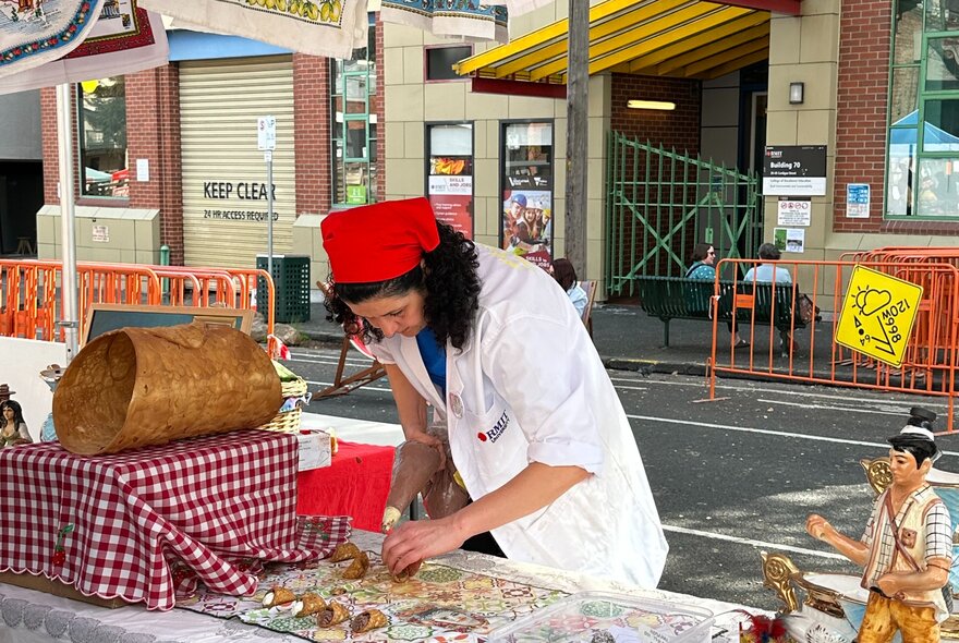 A woman making cannoli at an outside stall.