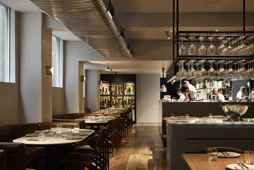 Interior of Nomad restaurant showing tables set and ready for dining patrons, with the open kitchen area visible in the background.