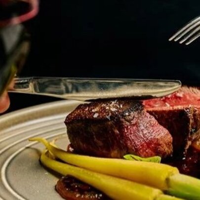 Plate of meat and vegetables with a glass of red wine.